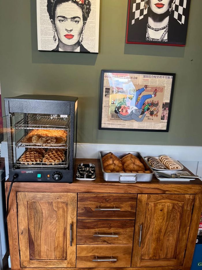 Brunch-Station mit Waffeln, Croissants und Gebäck unter einem Porträt von Frida Kahlo