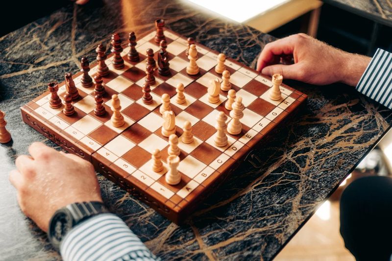 Zwei Hände spielen Schach auf einem Holzbrett auf einem Marmortisch